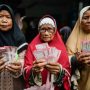 Warga memperlihatkan uang tunai bantuan sosial (bansos). (Foto: Antara)